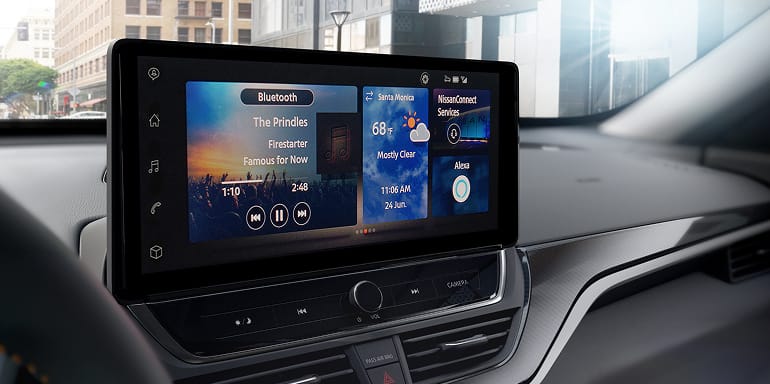 A large car display shows Bluetooth music playing The Prindles - Firestarter, Santa Monica 68°F Mostly Clear, NissanConnect Services, and Alexa.